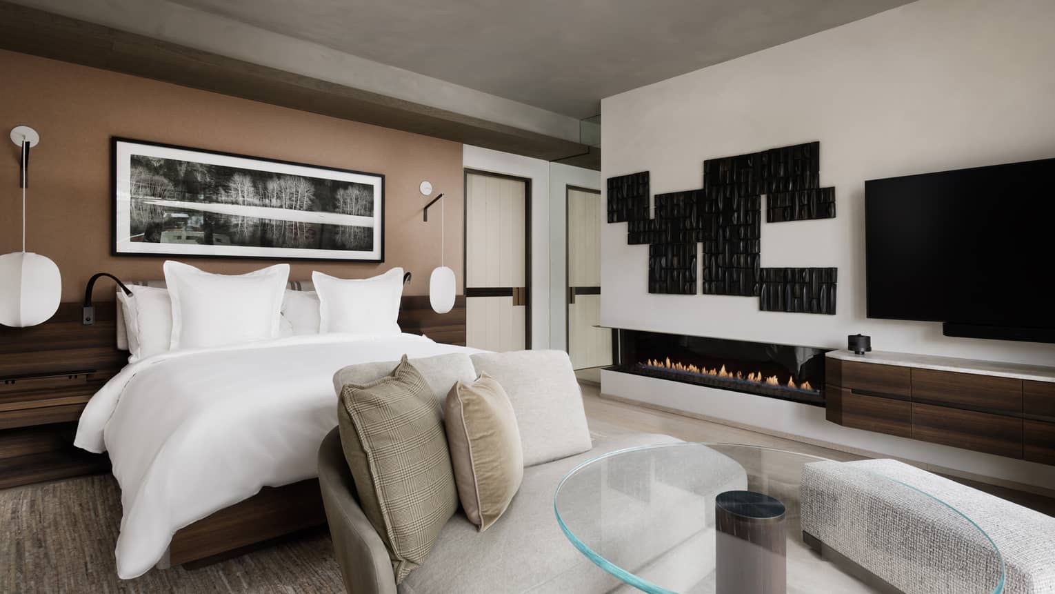 Bedroom with king bed, TV, small glass table and chaise