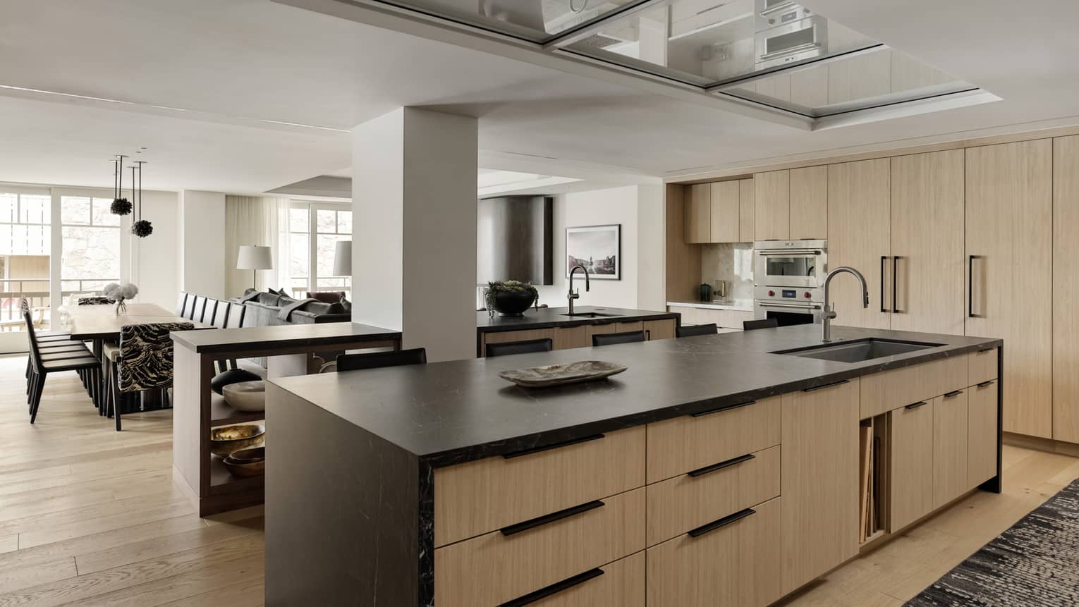 Modern kitchen island with light wood cabinets and dark counter