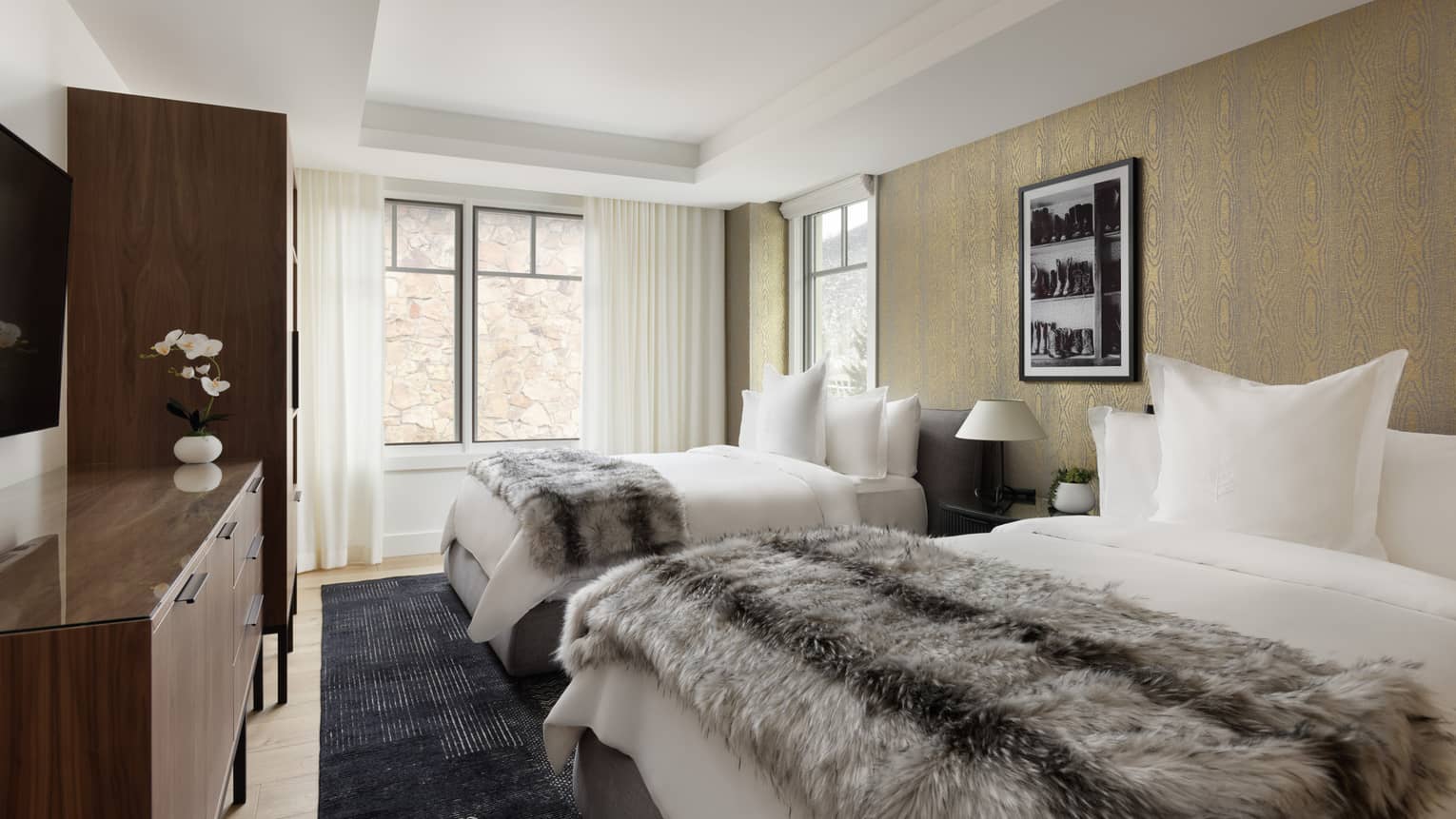 Stylish bedroom with two double beds, each with faux fur throws