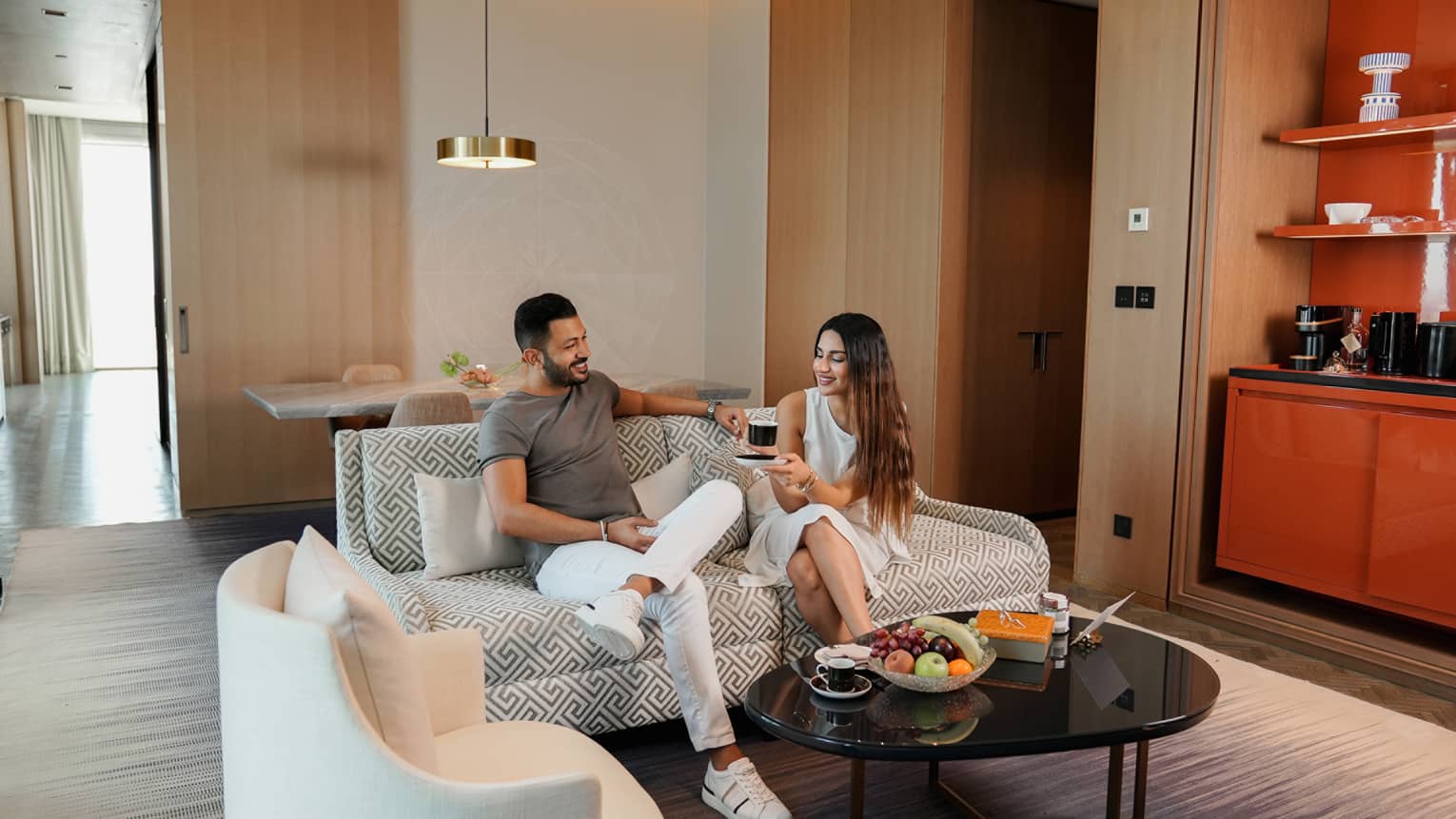 Man and woman sit on sofa in hotel suite