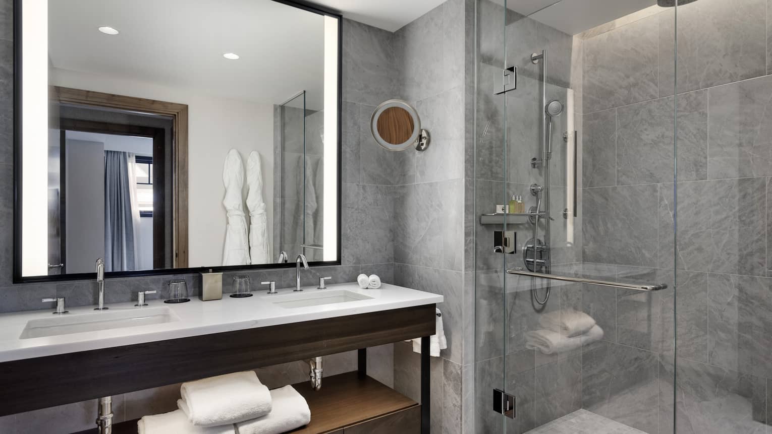 Modern bathroom with walk-in glass shower, double vanity and illuminated mirror