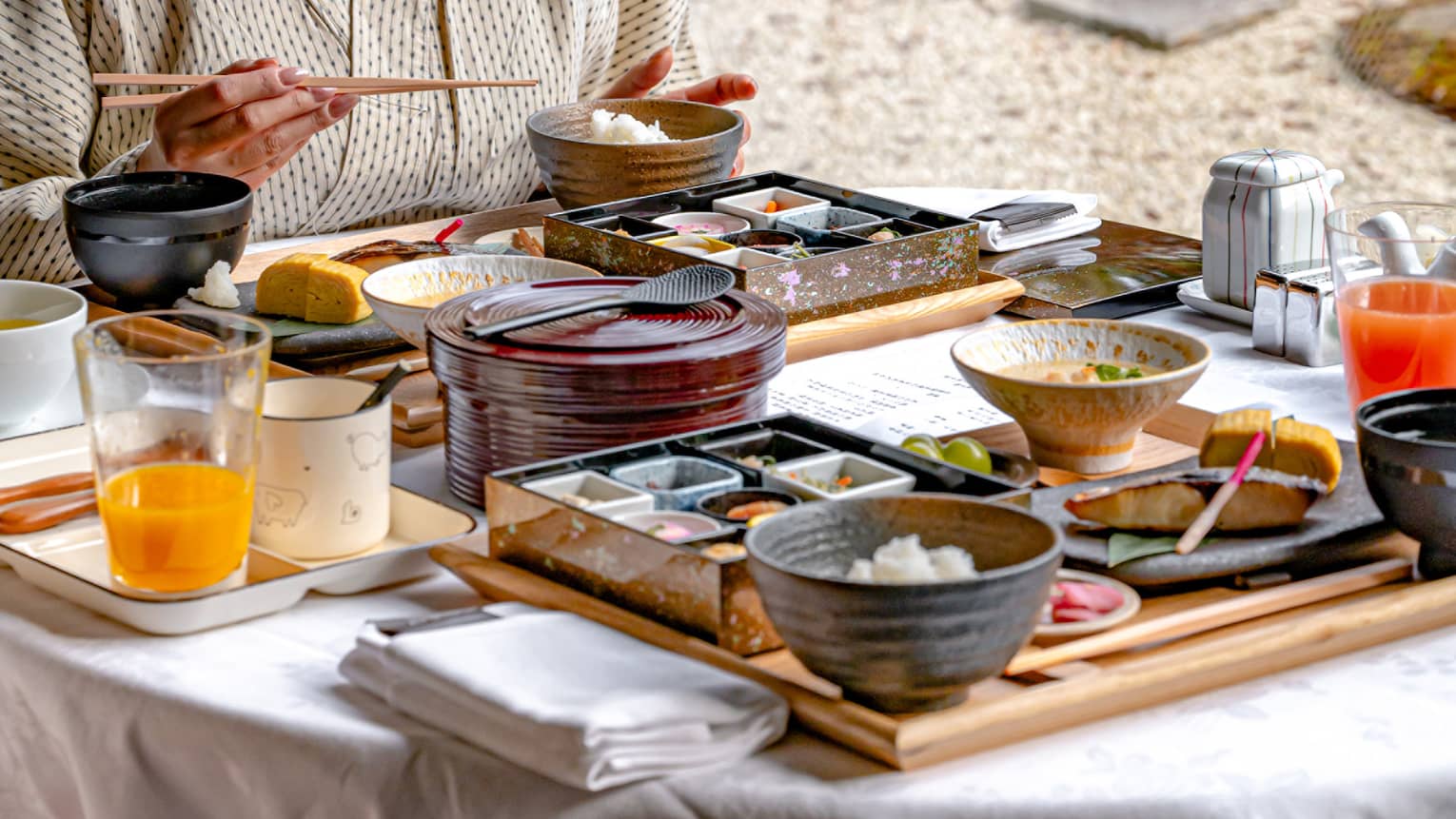 Woman eats breakfast in luxury hotel looking out window to garden