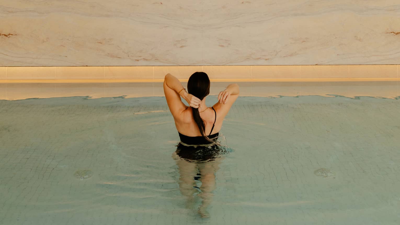 Person wearing a swimsuit and standing in the pool water.