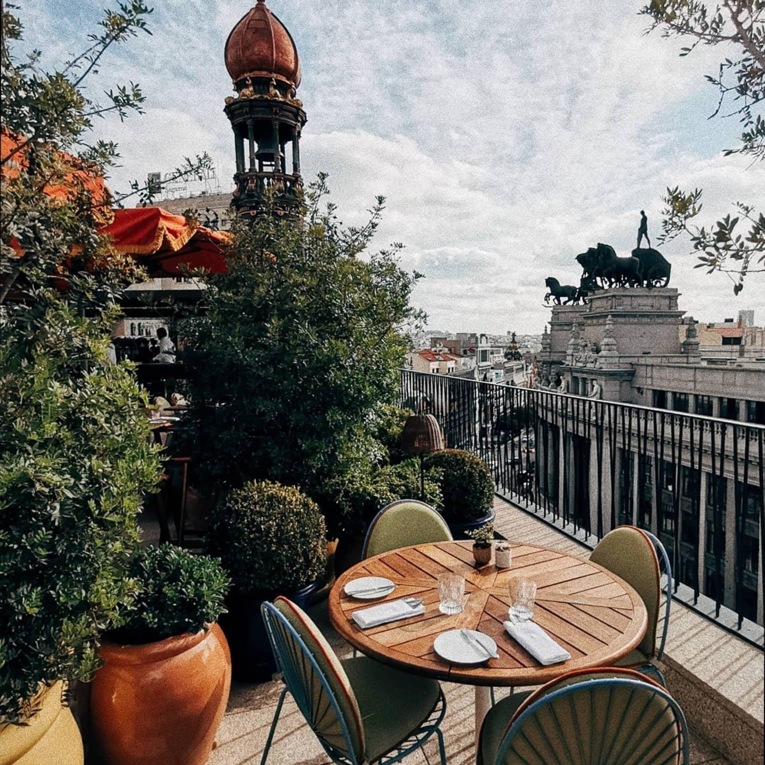 An outdoor dining table on a terrace with a view of Madrid