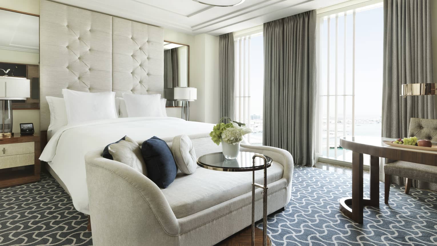 Superior Room plush white sofa with cushions at foot of bed with tall white padded headboard