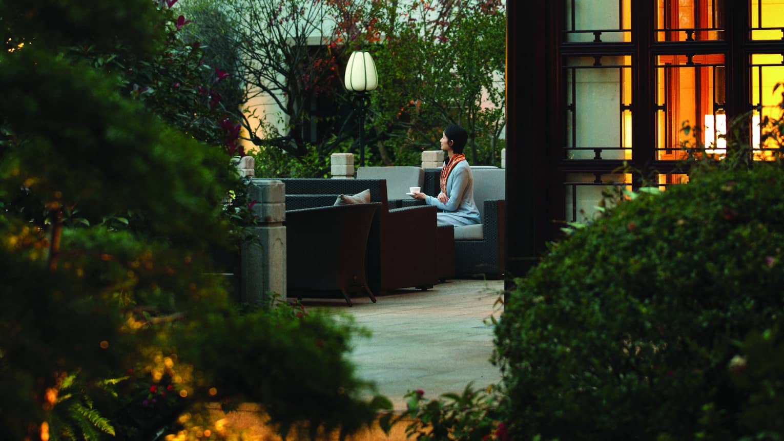 Person sits in outdoor courtyard surrounded by two-storey building with traditional Chinese architecture