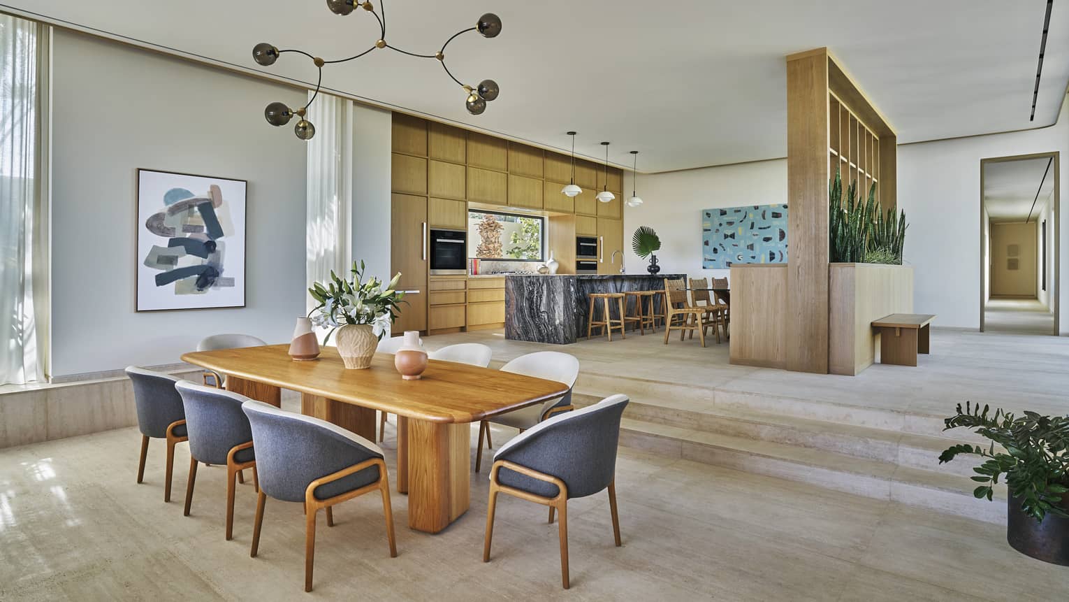 Spacious great room with dining table for 8, and three steps leading up to a modern kitchen, in a private villa at Four Seasons Resort and Residences Los Cabos
