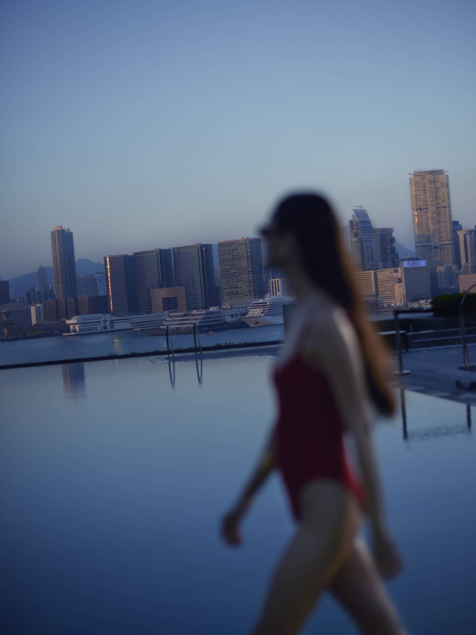 Woman walks along the edge of luxury hotel pool in city