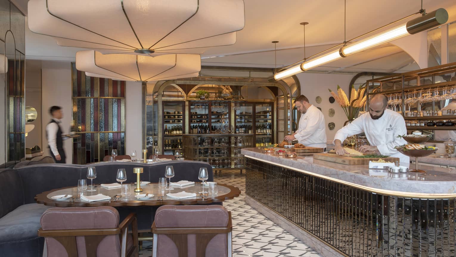 Miss River dining area with viewing kitchen, two prep chefs at work, passing waiter