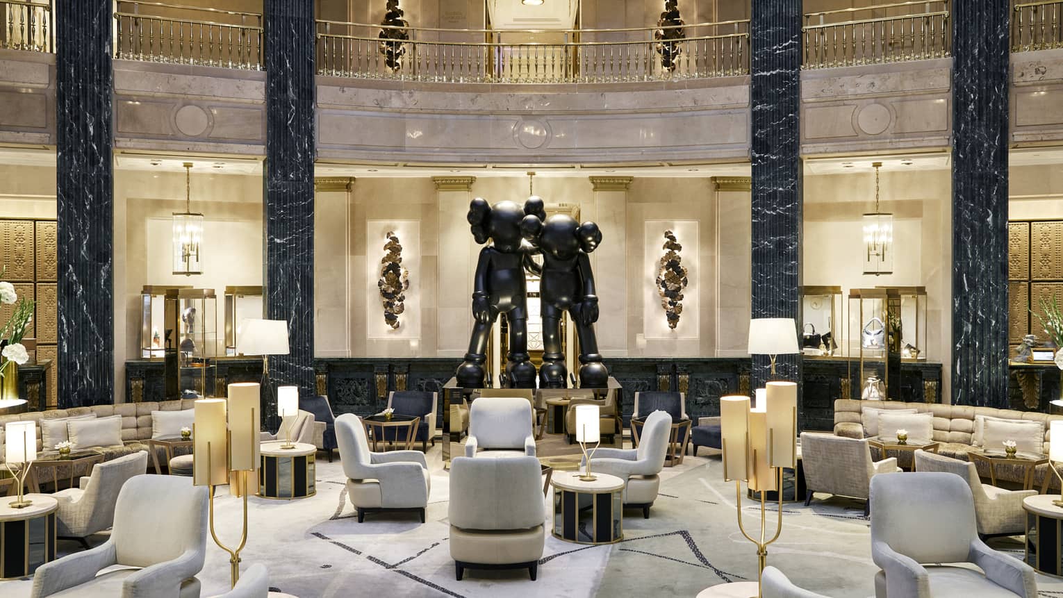 A spacious hotel lobby with a large seating area, black marble columns and a statue