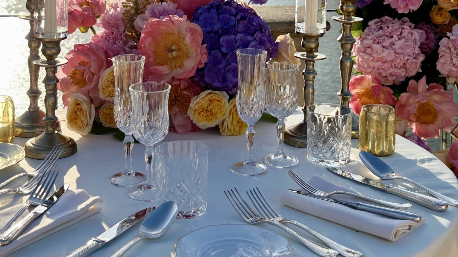 An elegantly set outdoor dining table overlooking a river, with bridges and city views in the background