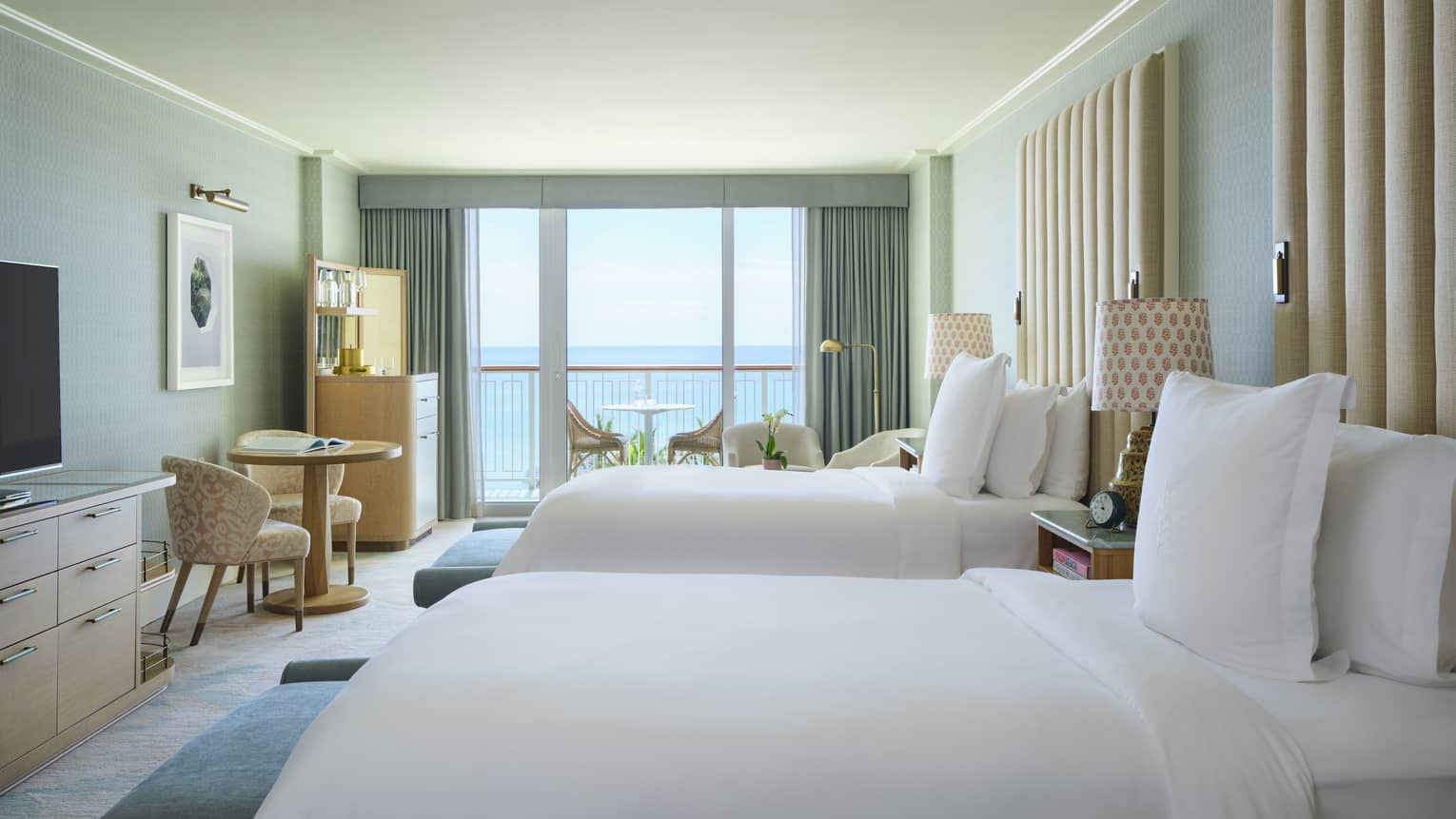 Luxury resort room with two beds, small table and chairs, and ocean-view balcony at Four Seasons Resort Palm Beach