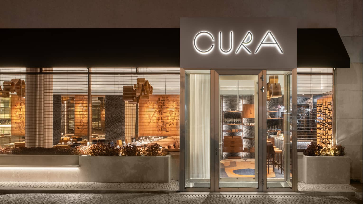 Exterior of CURA restaurant illuminated at night