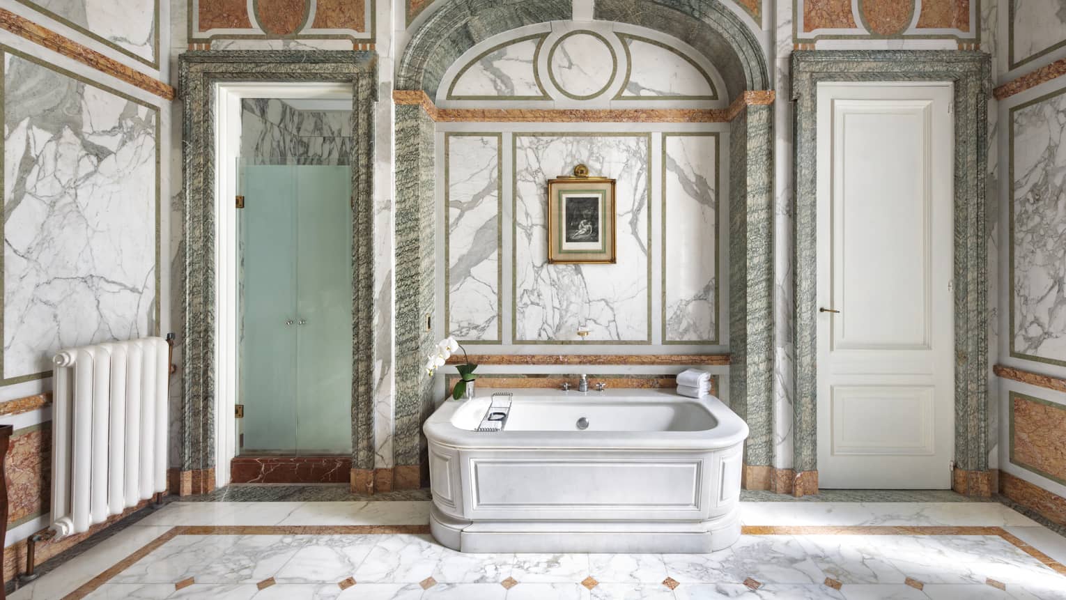 Bathroom with white marble bathtub, white-and-grey marble walls, green marble accents and tiled marble floors