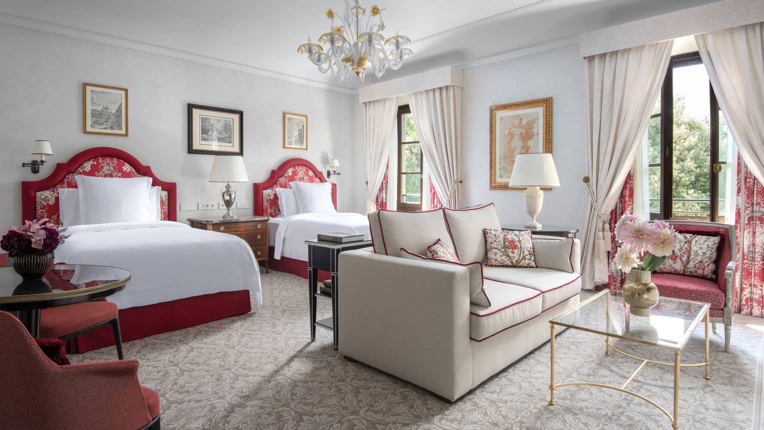 Luxury hotel room with two beds, chandelier, sitting room with sofa and arm chair, and elegant window drapery at Four Seasons Hotel Florence