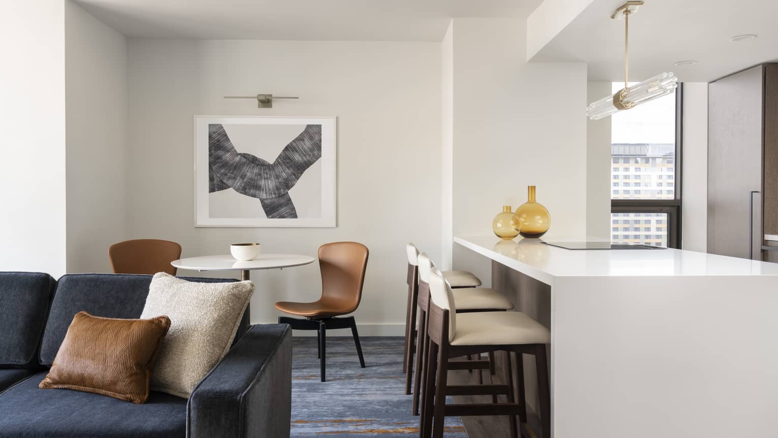 One-bedroom Residential Suite living area, dining area and kitchen with dark blue accents and bar stools