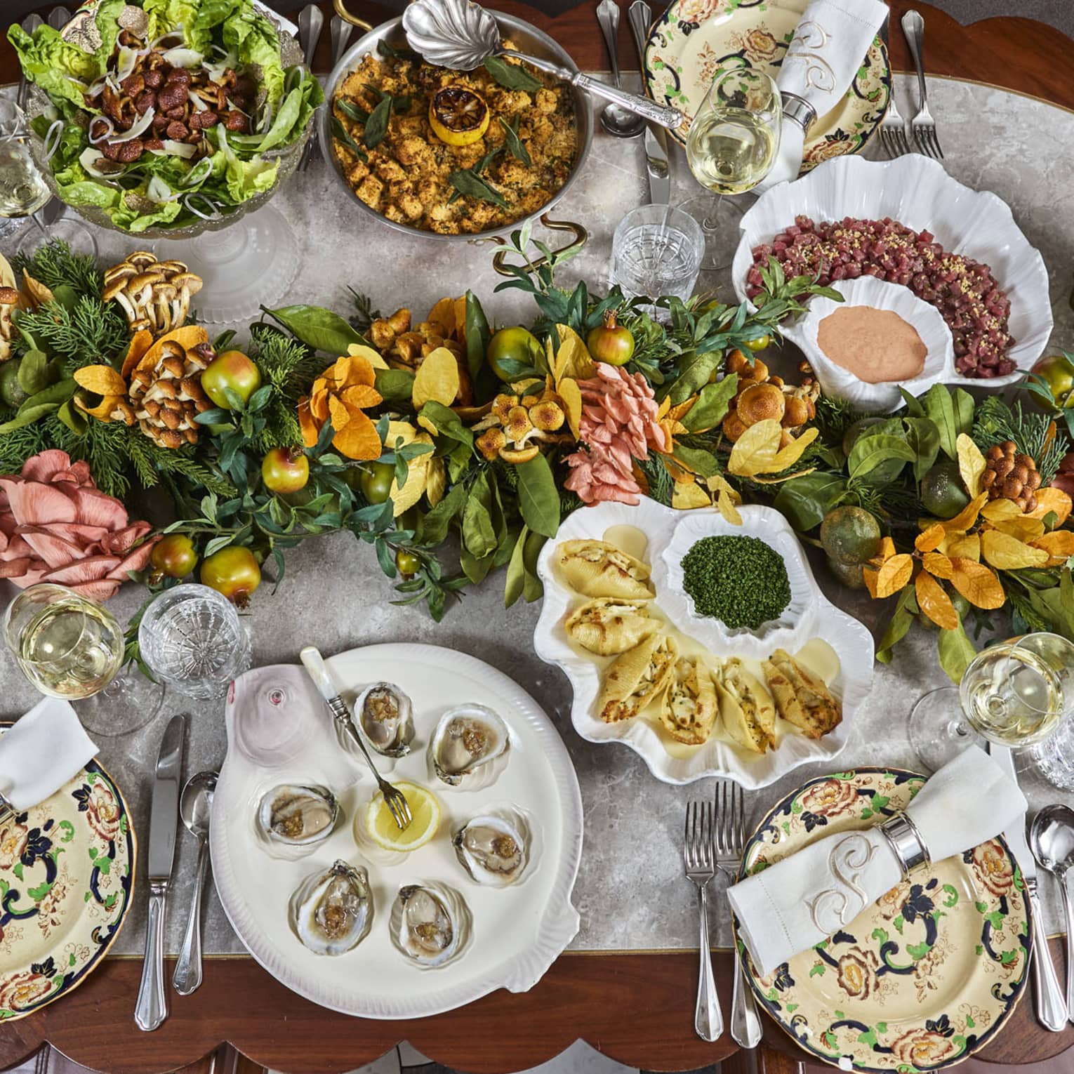 Many food dishes including clams and a salad bowl along with a table centrepiece.