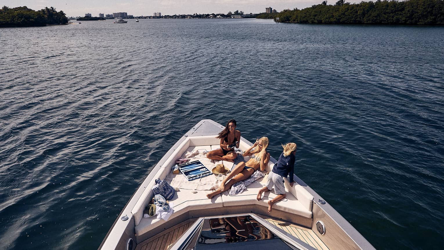 Three people lounging on the front of a boat deck.