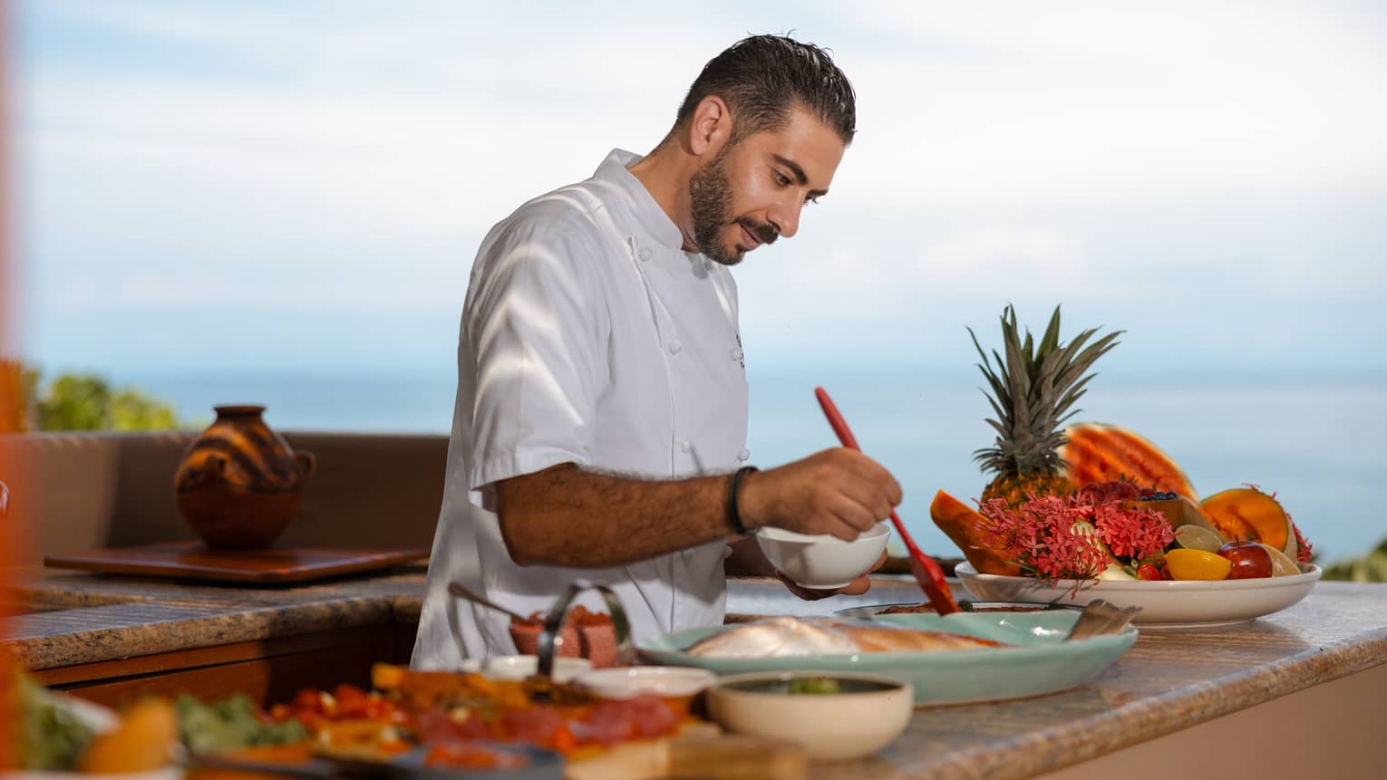 A chef prepares food in an outdoor cooking area.