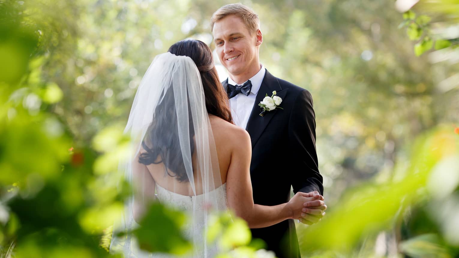 A person wearing a long veil dances joyfully with a smiling partner in a beautiful garden, surrounded by nature's splendor.