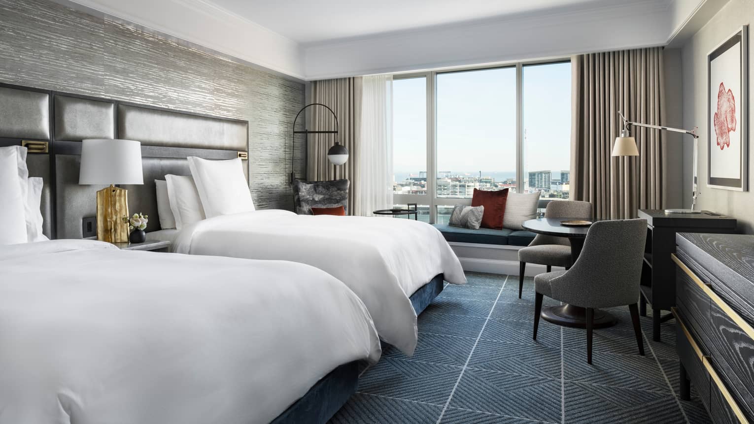 Room with two double beds, dark grid-like carpeting, large windows