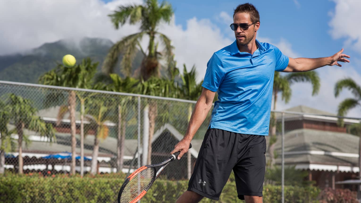 Tennis ball in air, man swings racket on court