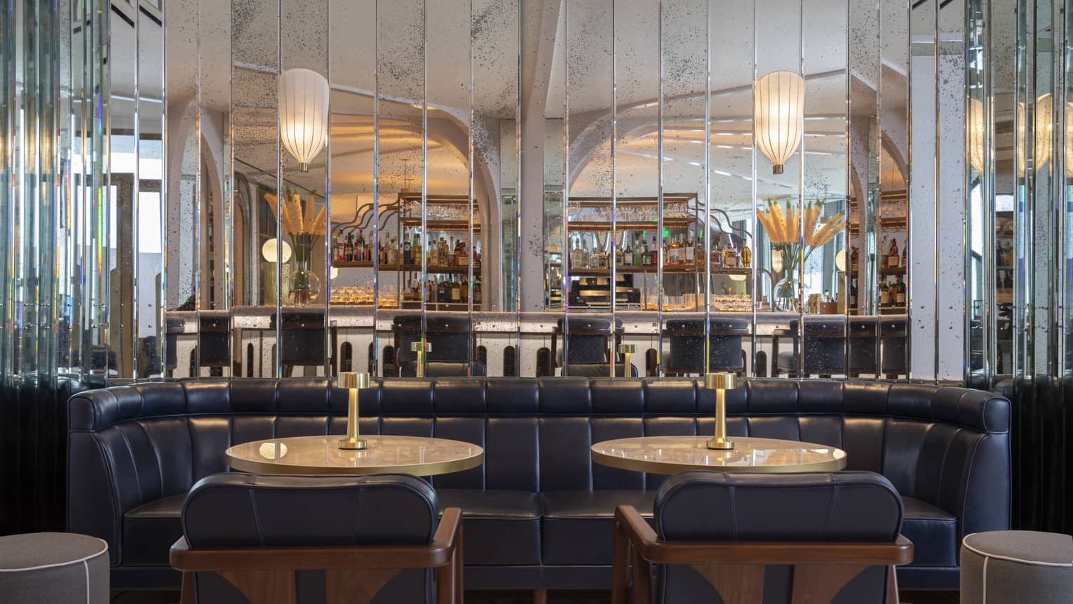 Miss River dining area with navy leather booths and chairs, round tables, mirrored walls, wall chandeliers