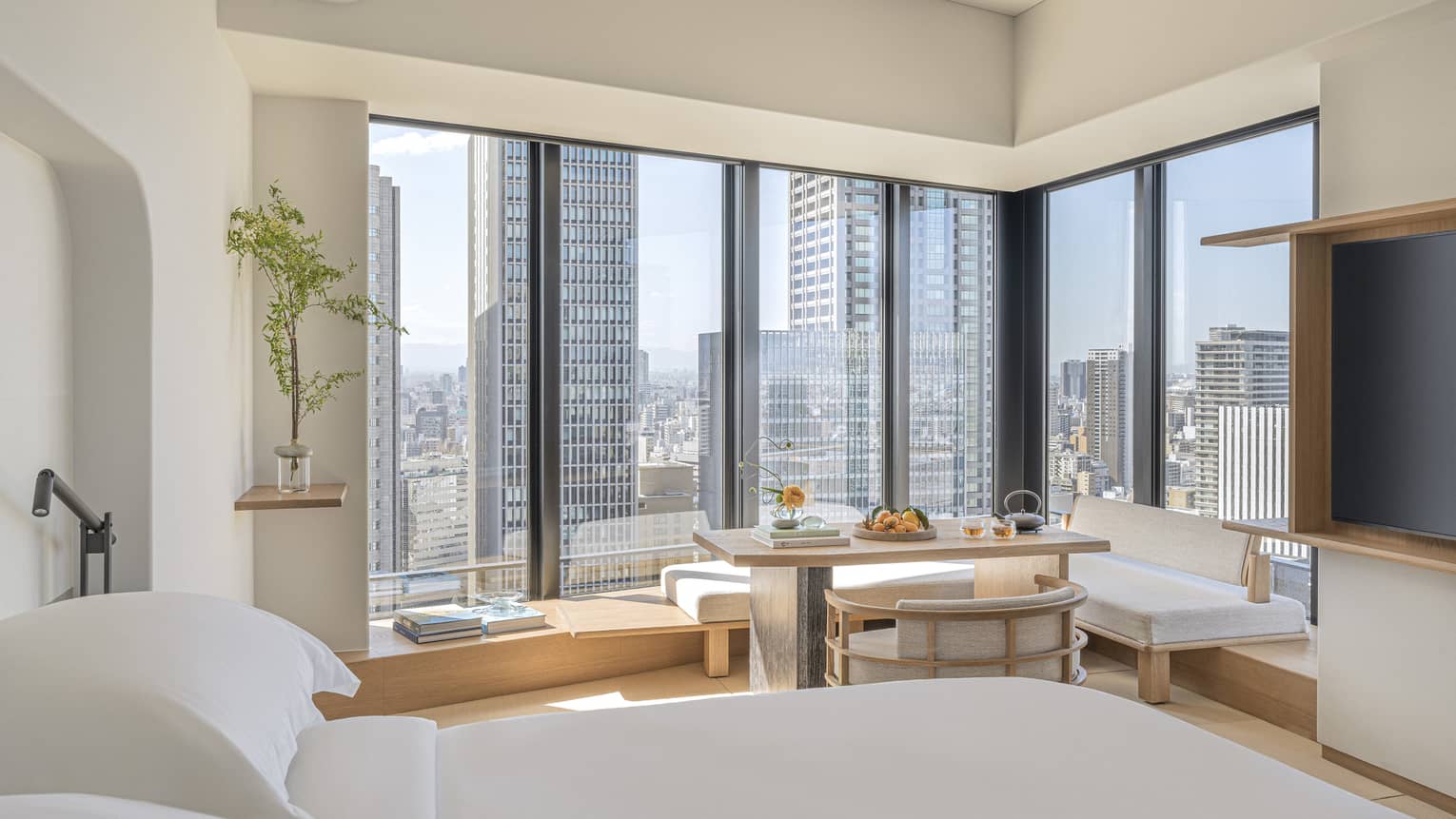 Luxurious guest room at Four Seasons Hotel Osaka with skyline views, modern decor, and serene seating area.