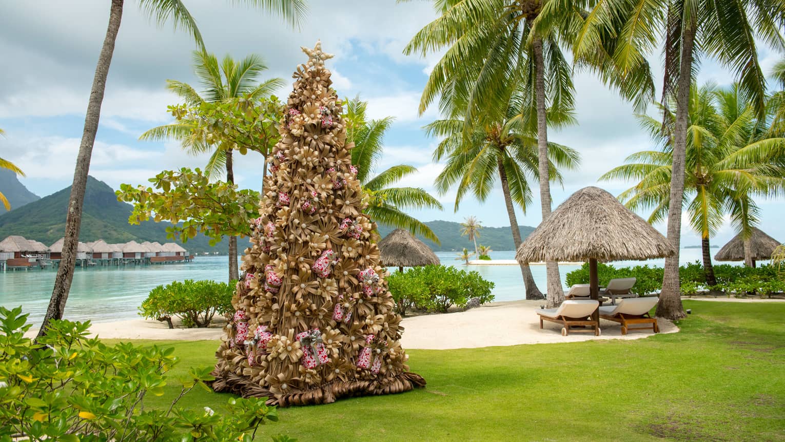 Decorative Christmas tree on resort lawn surrounded by palm trees