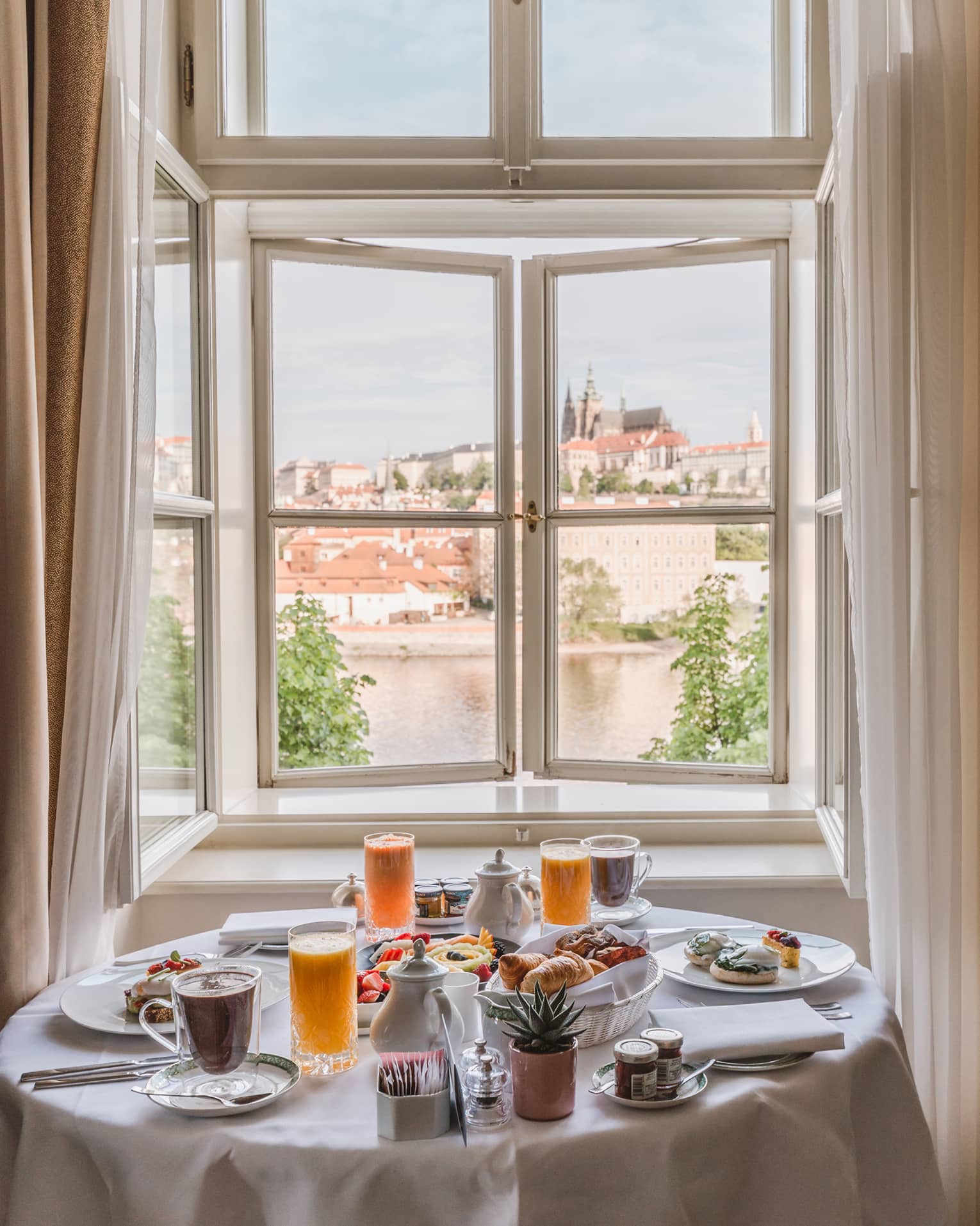 Alcove with round clothed table set for in-room breakfast with views of the Vltava River