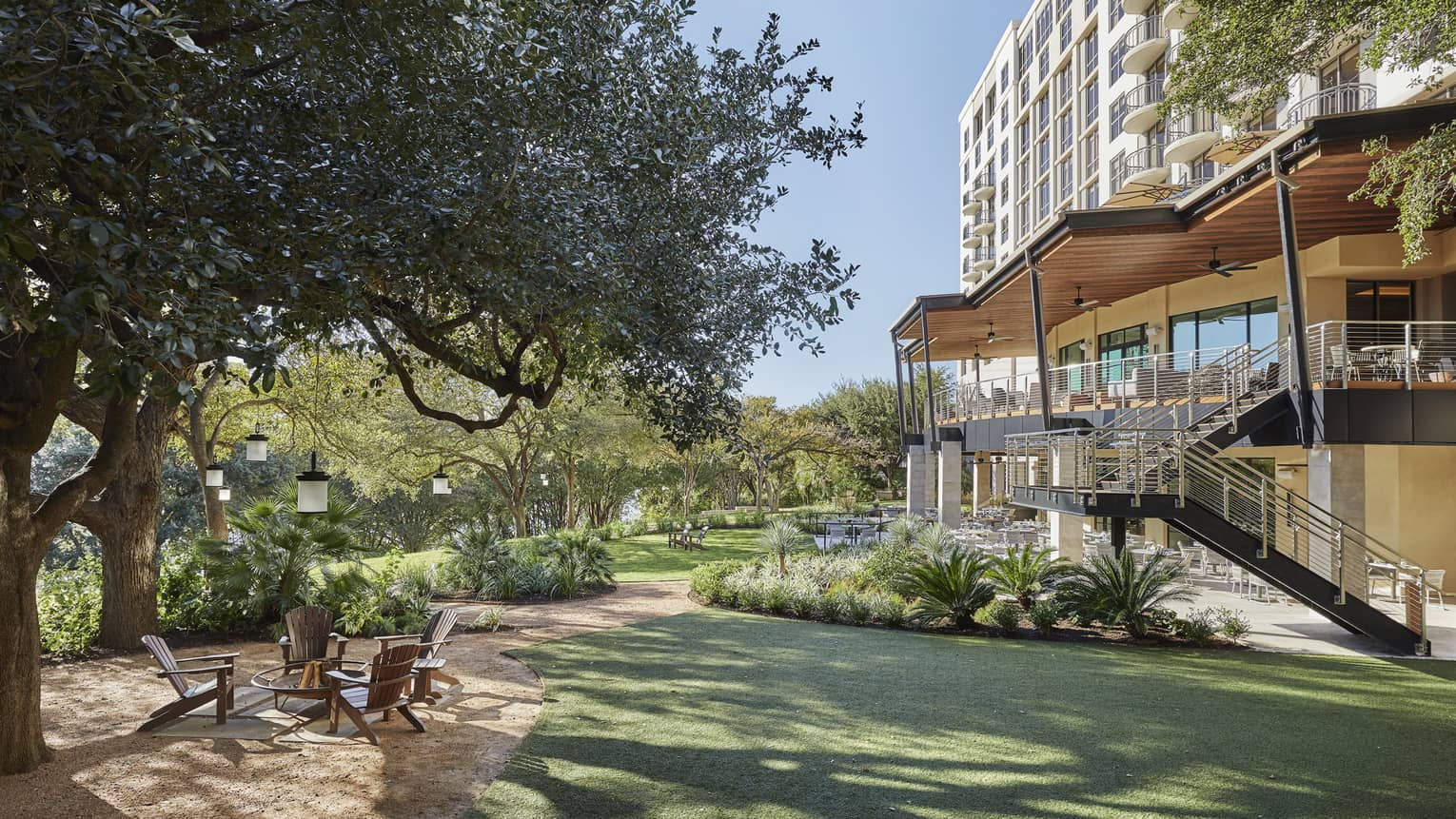 Exterior of Four Seasons Austin hotel with outdoor patio next to large tree and river