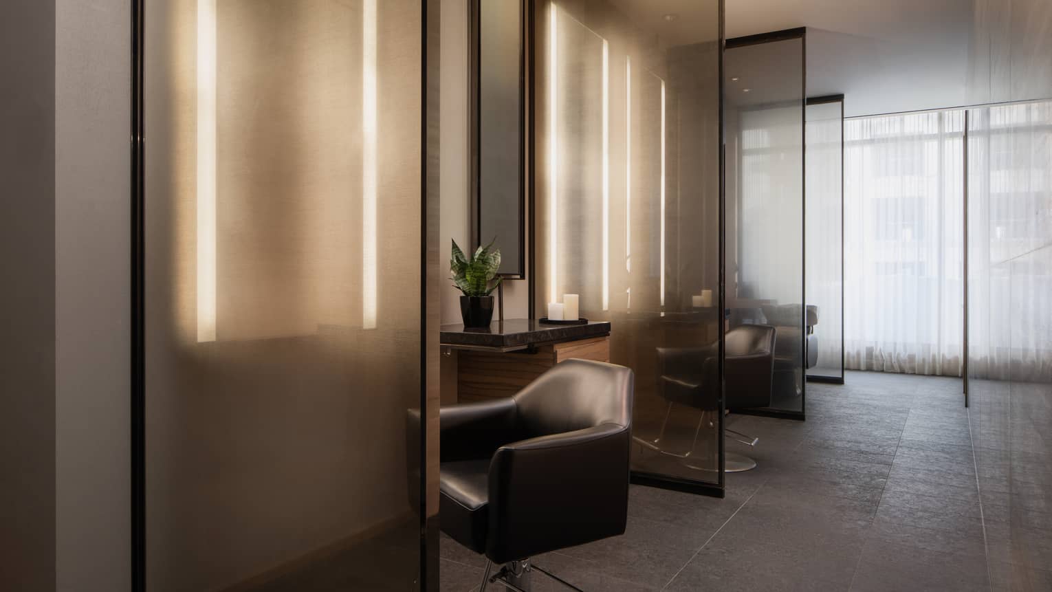 Salon with three partitioned stations and black leather swivel chairs