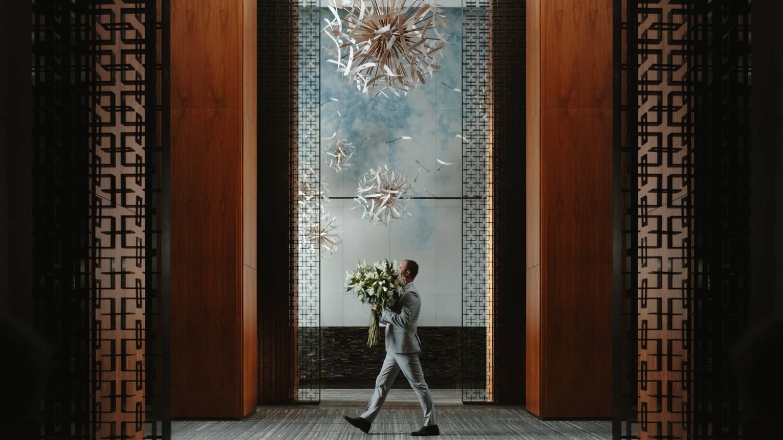 Man carries large floral arrangement through lobby of Four Seasons Hotel Toronto