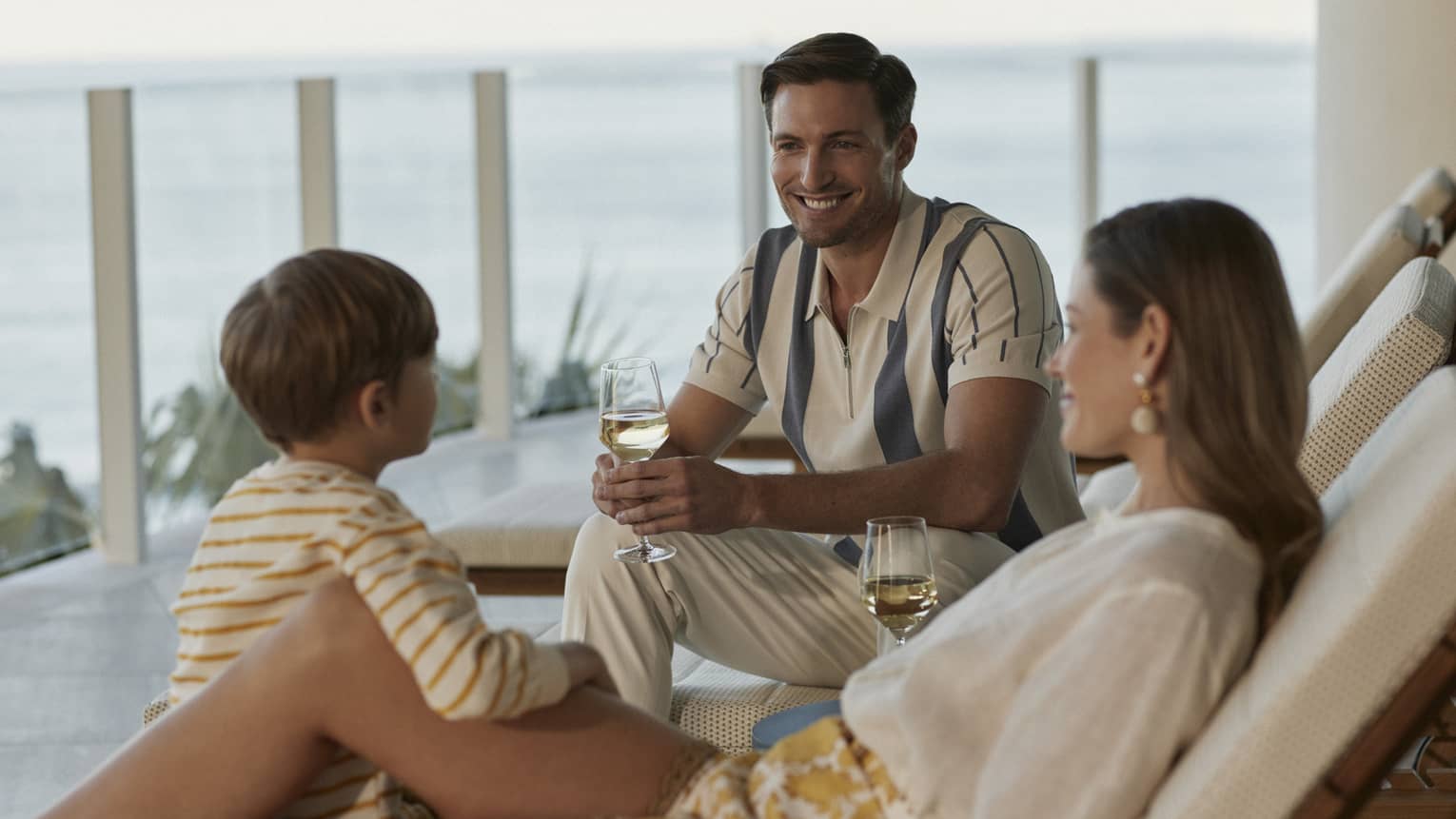 Family lounging in outdoor chairs with glasses of wine.