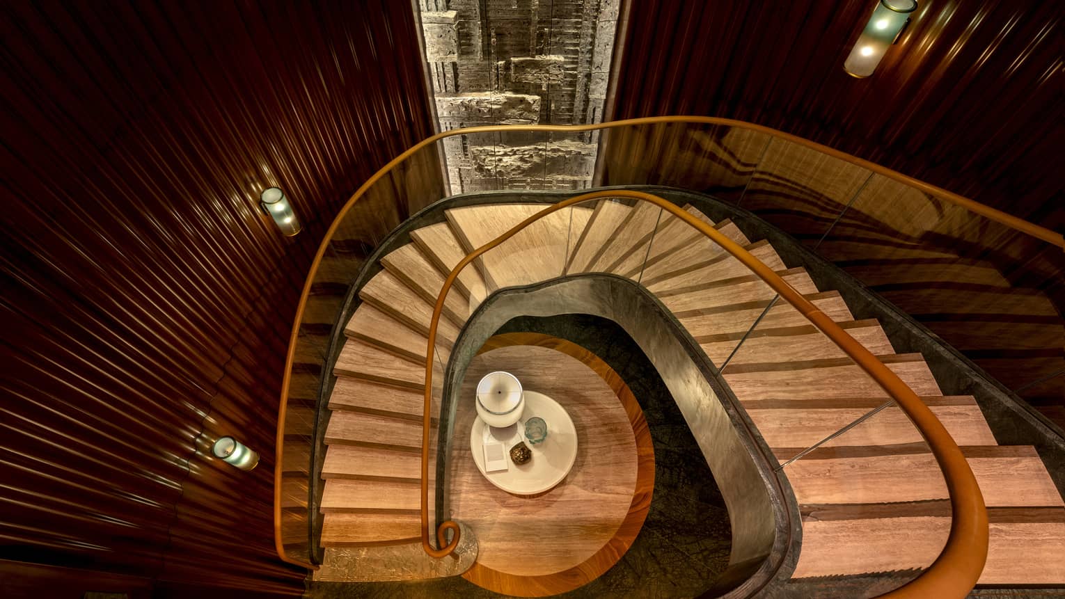 Aerial view of wooden staircase with gold bannisters curving to lower floor