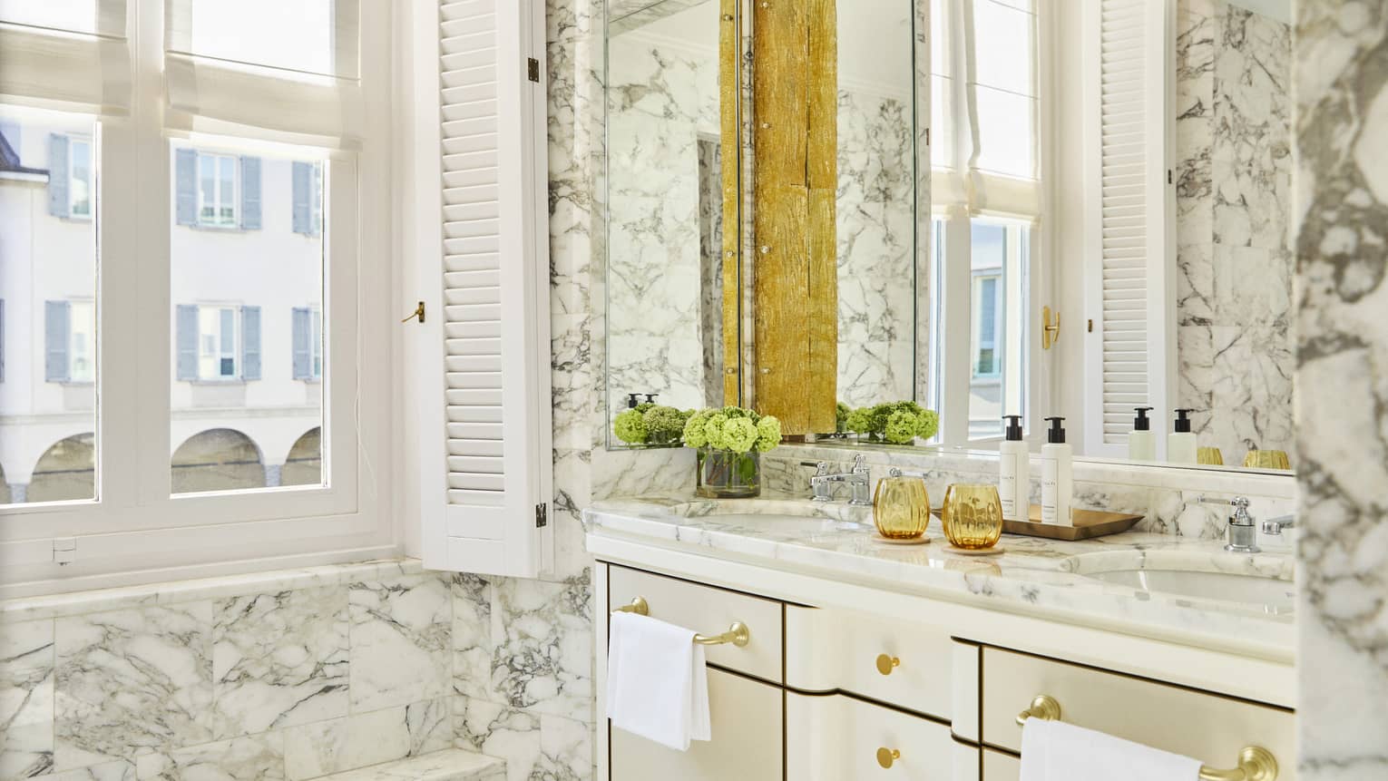 Italian marble bathroom of luxury hotel suite, featuring a window and double vanity