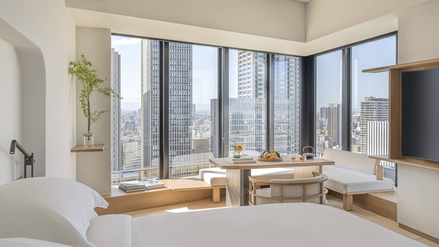 Luxurious guest room at Four Seasons Hotel Osaka with skyline views, modern decor, and serene seating area.