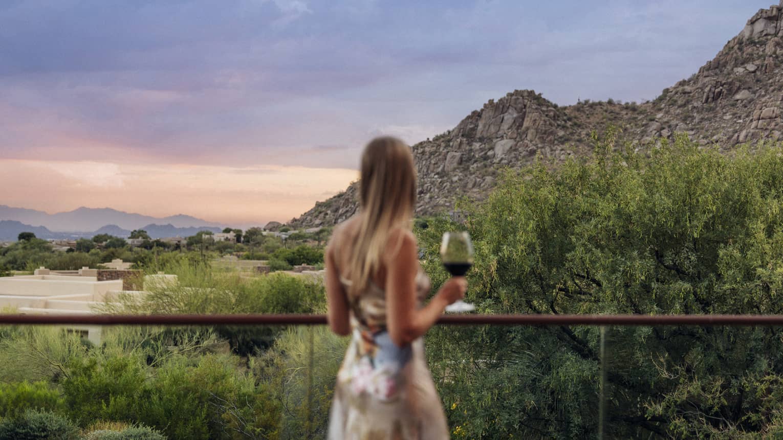 Woman looks out to mountain view from balcony at Four Seasons Resort Scottsdale