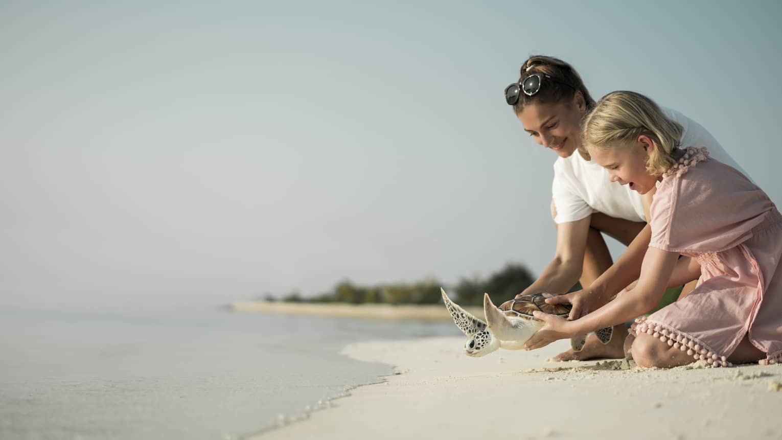 Marine Discovery Centre. Woman and daughter help release a sea turtle back in ocean