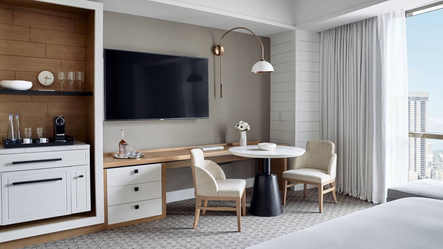 Modern suite at Four Seasons with a flat-screen TV, cosy seating area and well-equipped minibar, offering city views.