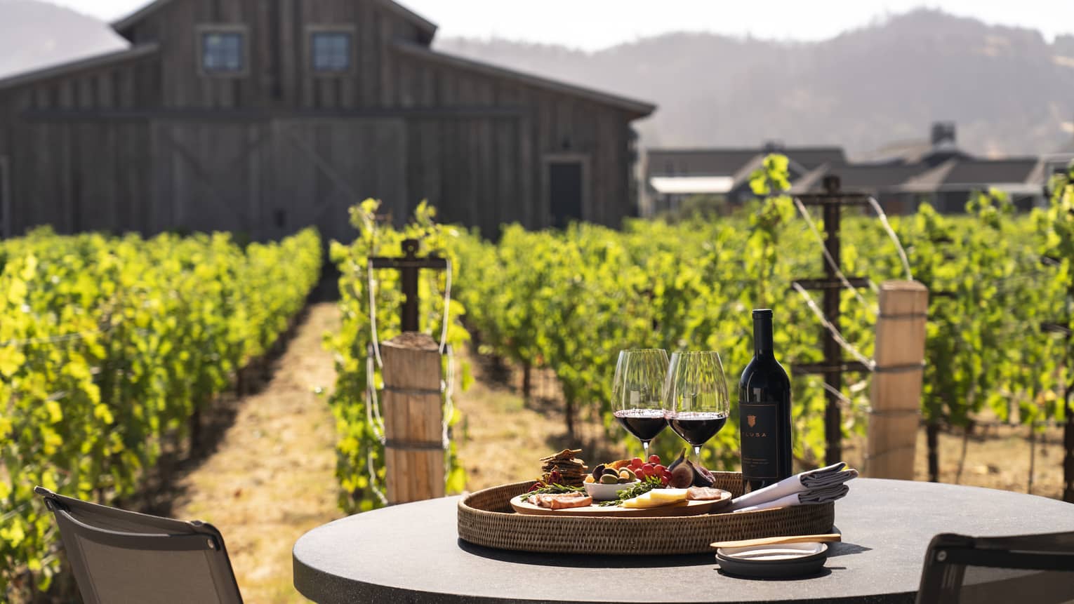 Two wine glasses with a plate of snacks on an outdoor dining table.