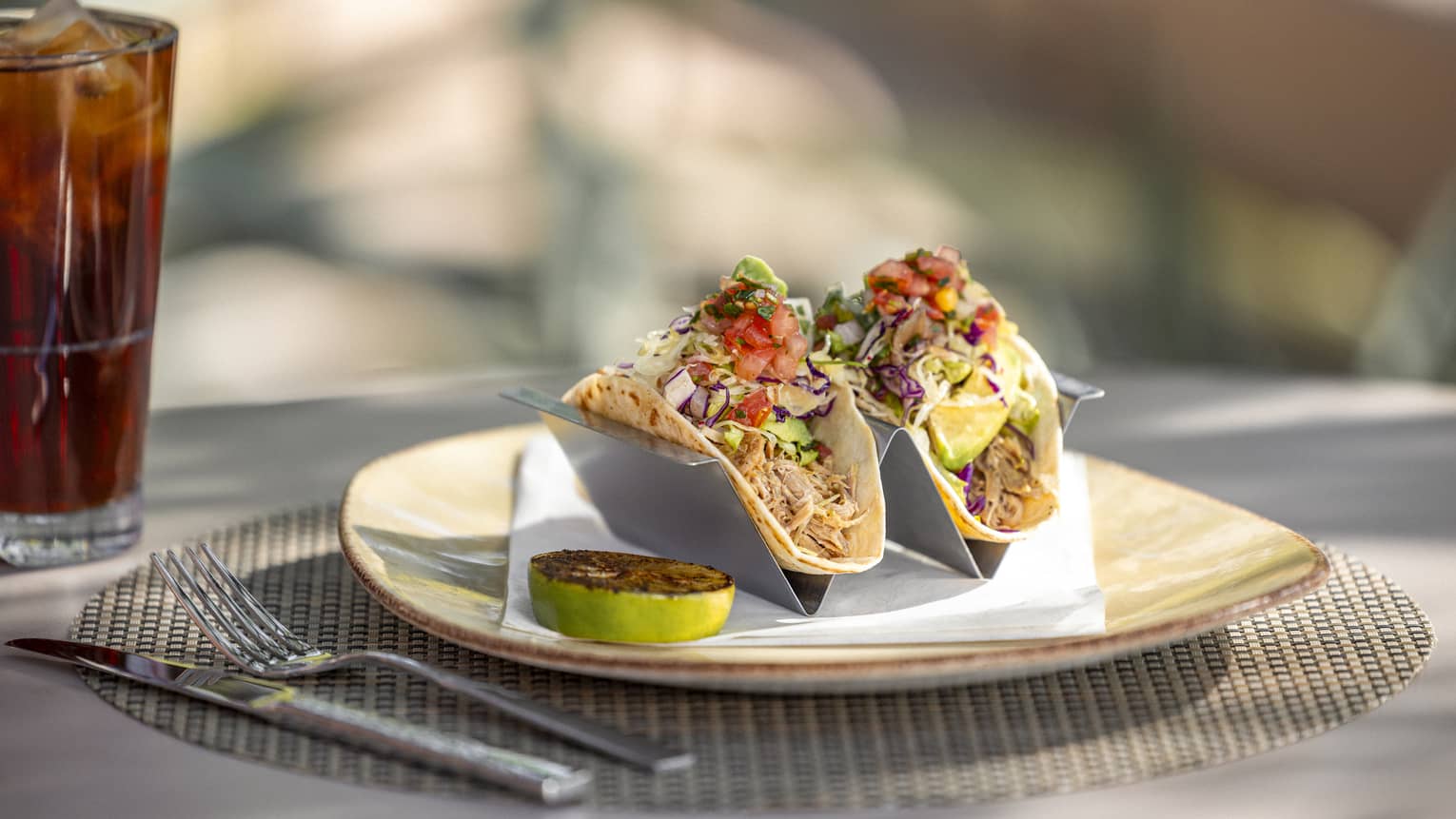 Chicken tacos on plate beside beverage