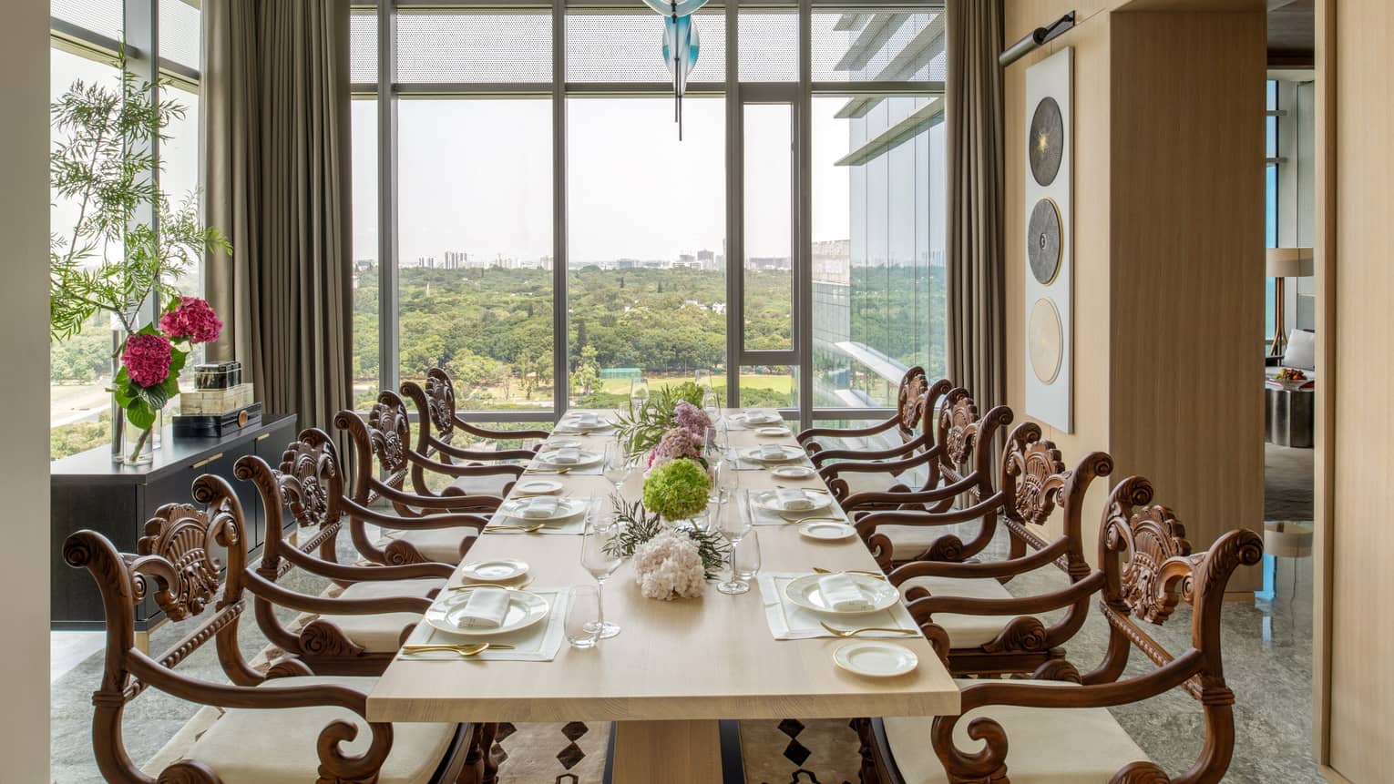 Guest room dining area with long rectangular eight-seater table , floor-to-ceiling windows with city views