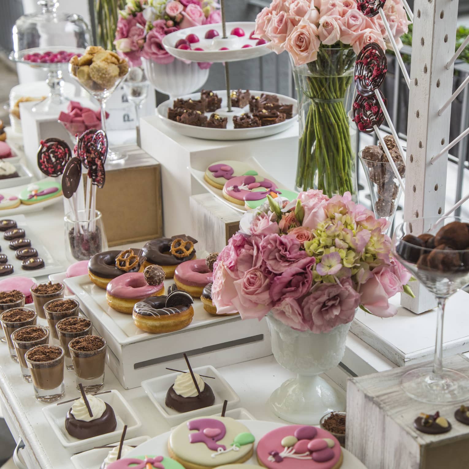 A table with cookies, donuts, cakes and bouquets of flowers