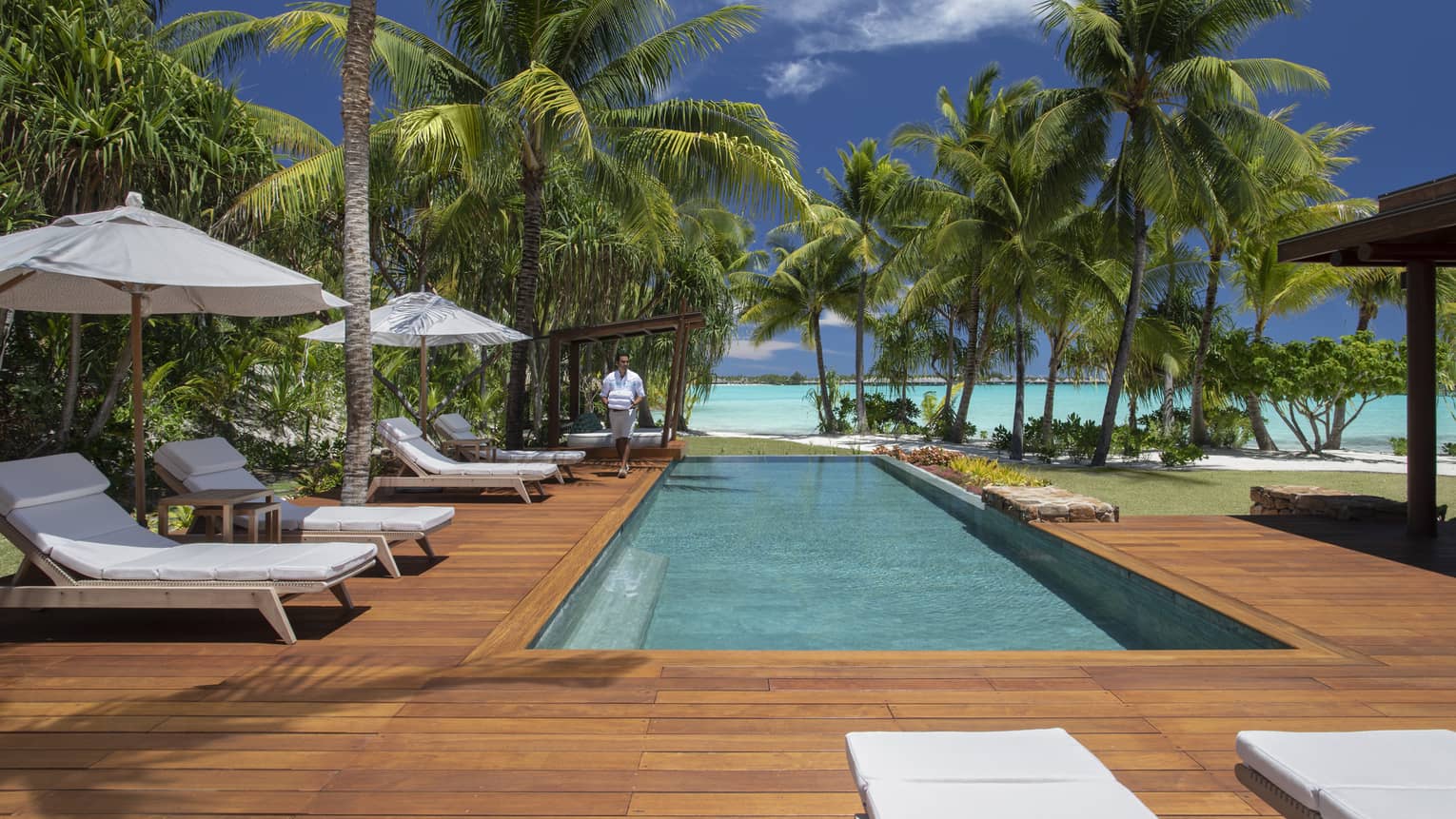 Villa's private pool with a lagoon view, surrounded by a wooden deck with sun chairs