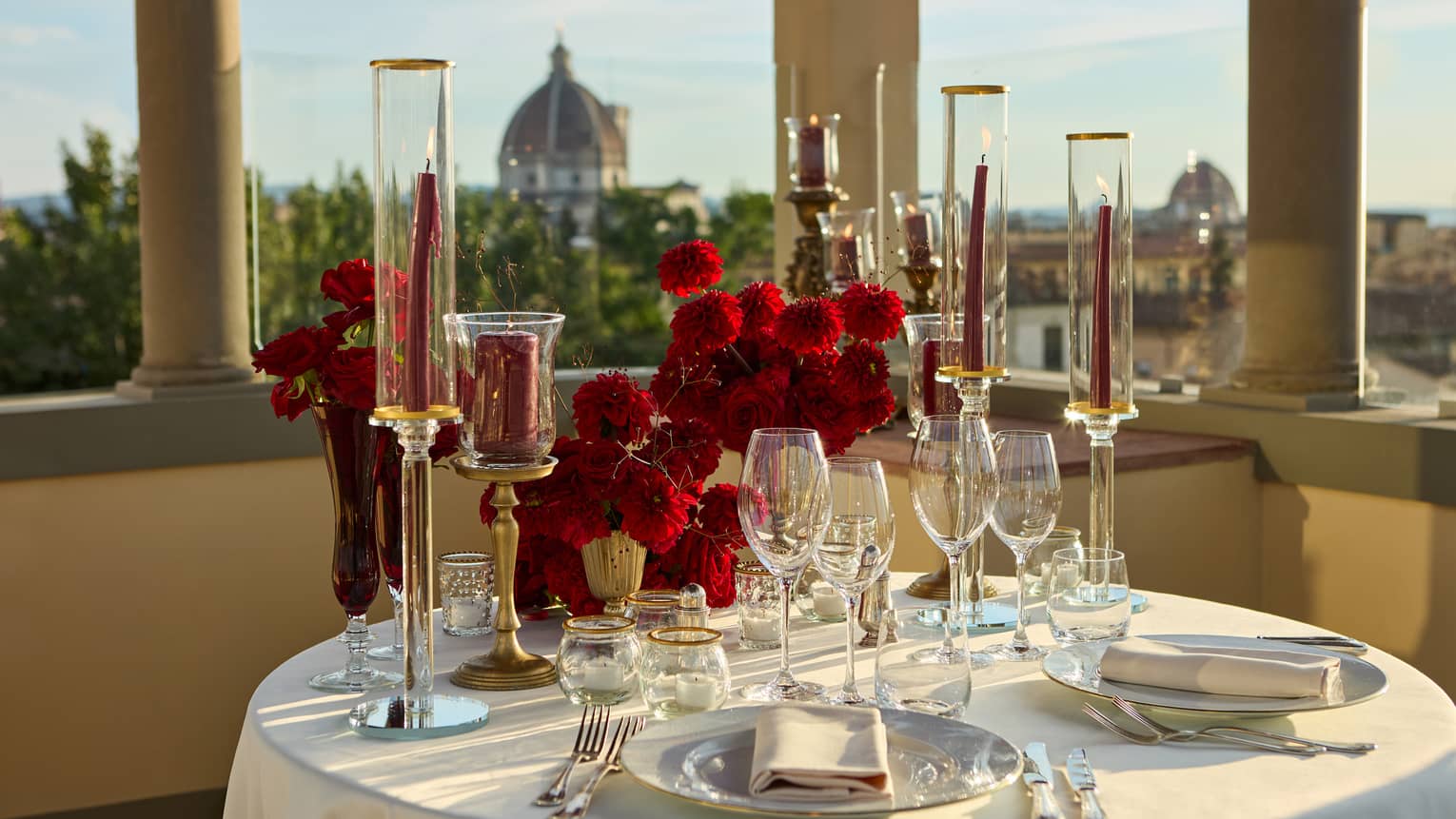 Terrace with elegant, romantic table set for two with crystal glassware and candlesticks looking out to the Duomo