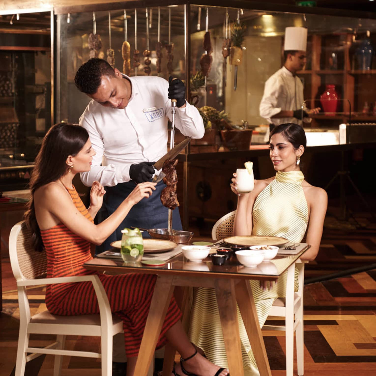 Two people at restaurant are served churrascaria off carving spit from chef