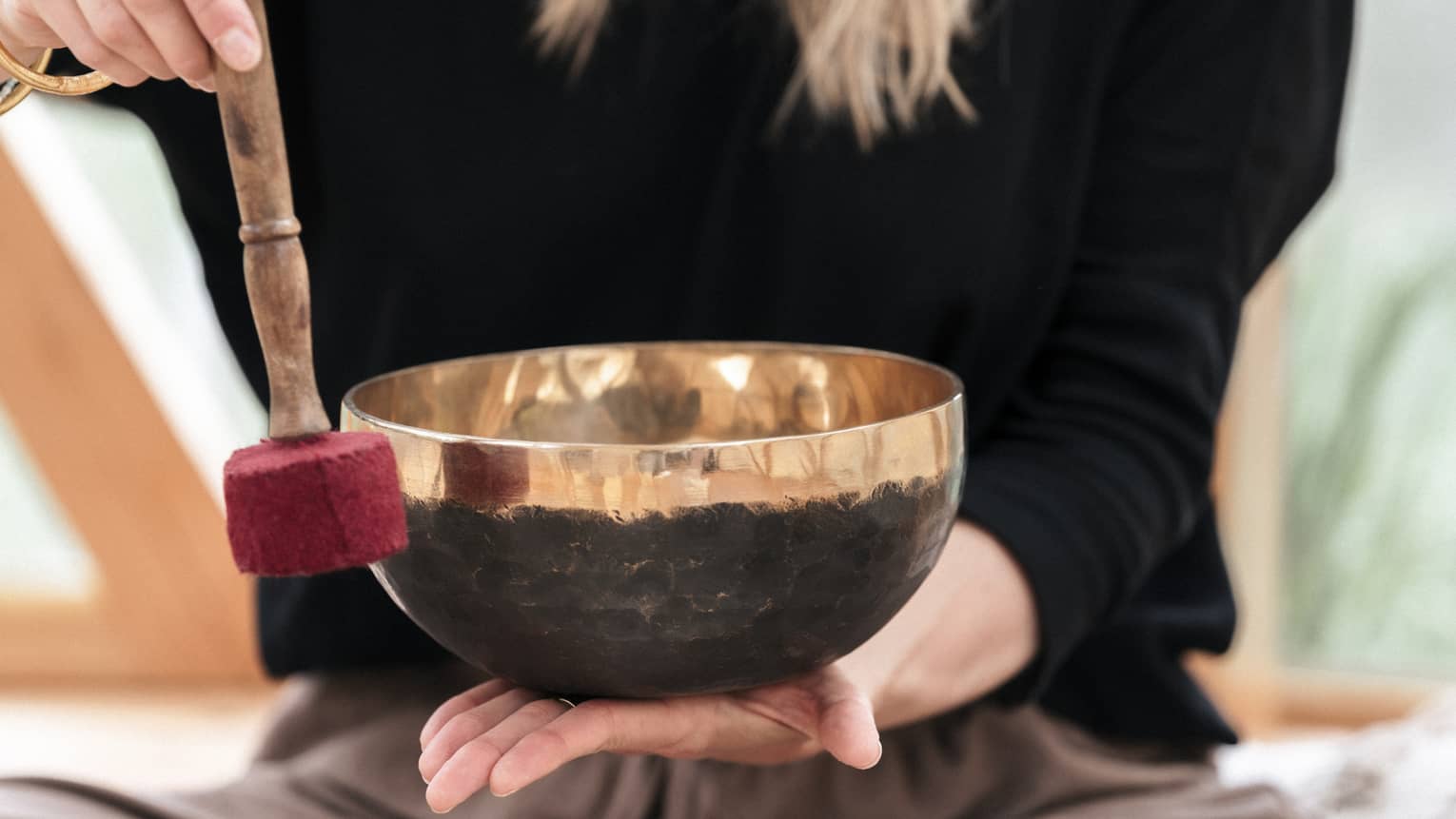 A person holding a Tibetan bowl and mallet