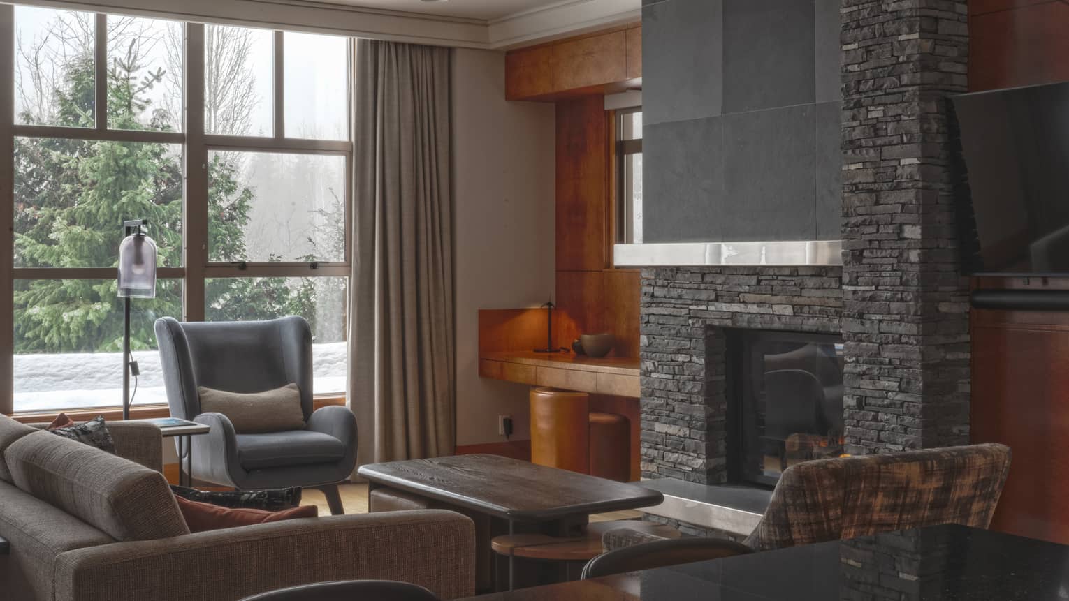 Contemporary living room of a private residence, with charcoal-coloured sofa and stone fireplace