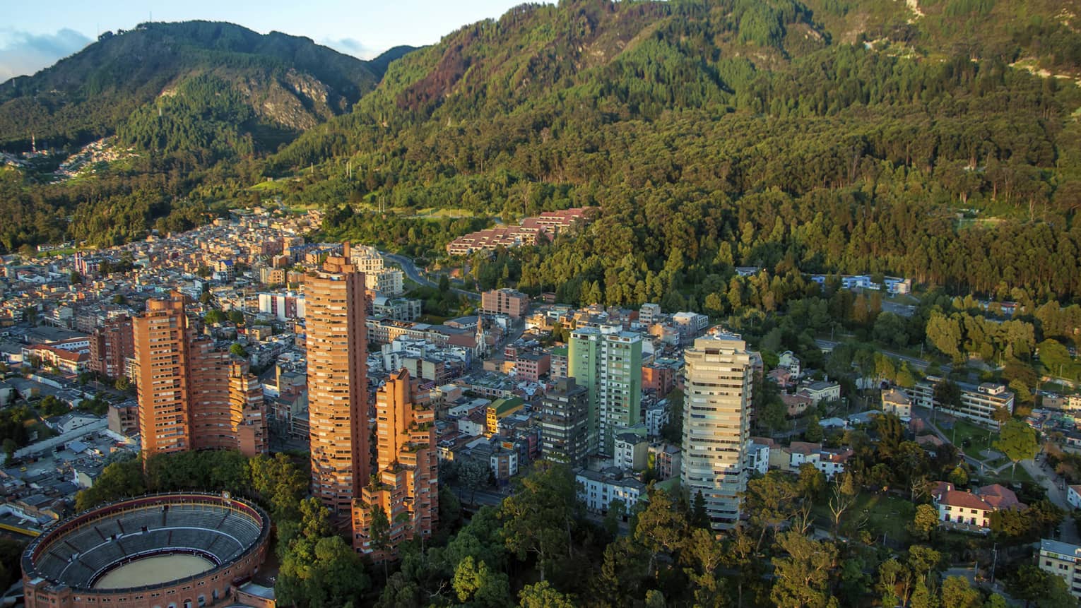 Aerial view of Bogota city high rises, houses and dome sports field on sunny day